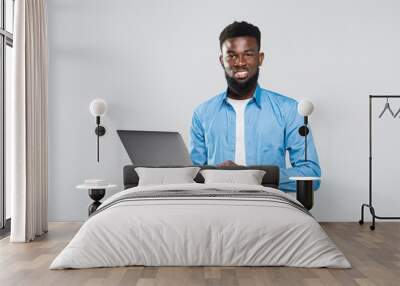 Young smiling african man standing and using laptop isolated over gray background Wall mural